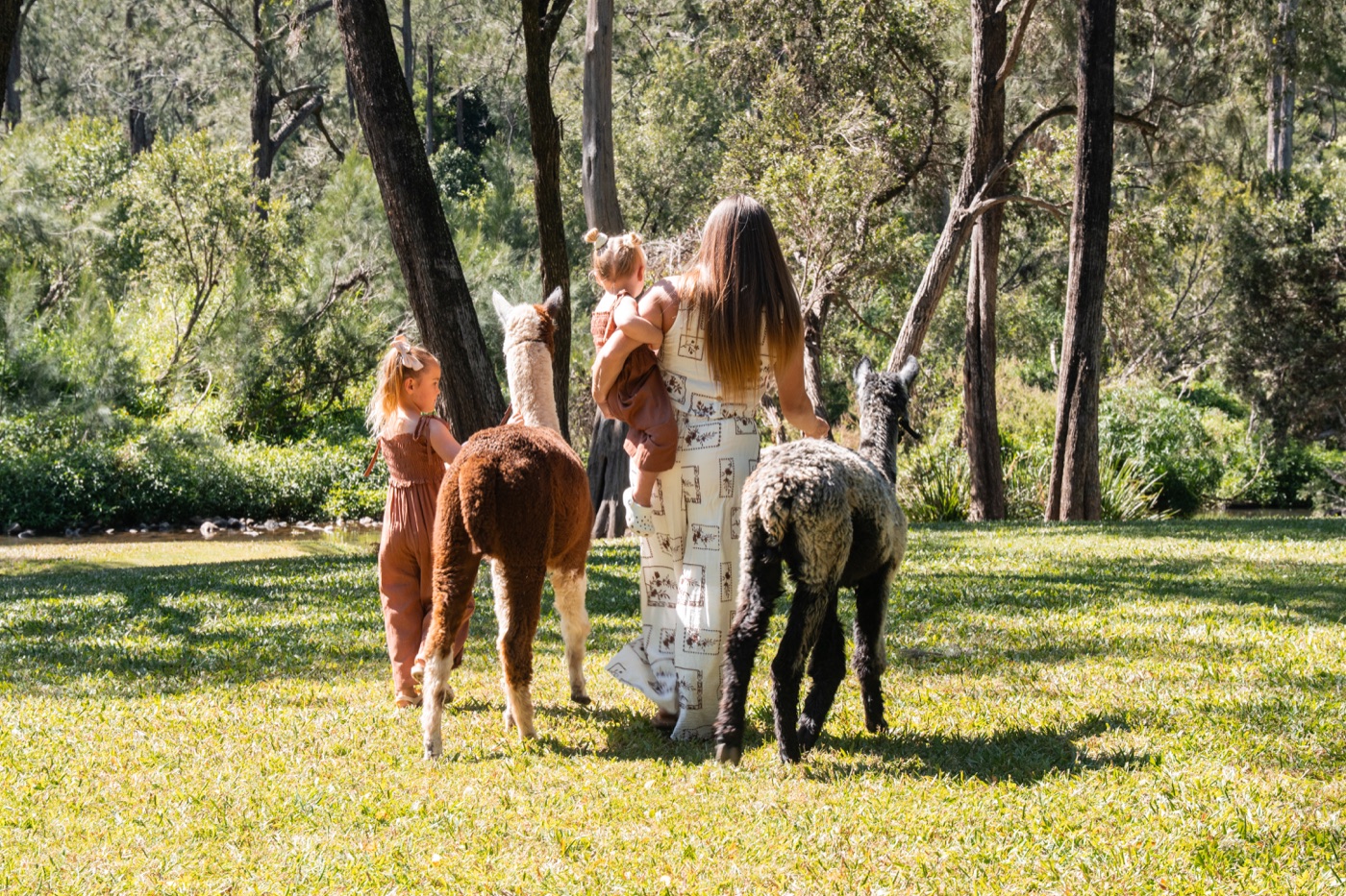 A mother and two young children walking two alpacas through the grounds at Historic Rivermill