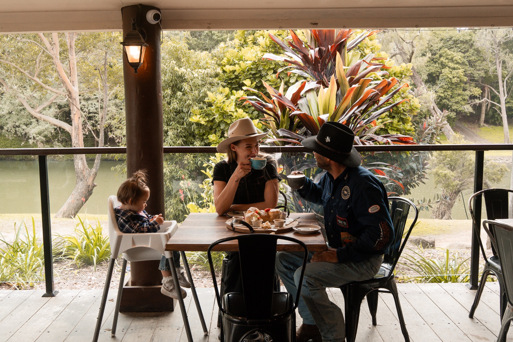 A family enjoying coffee and scones on the Rivermill Café deck overlooking the river