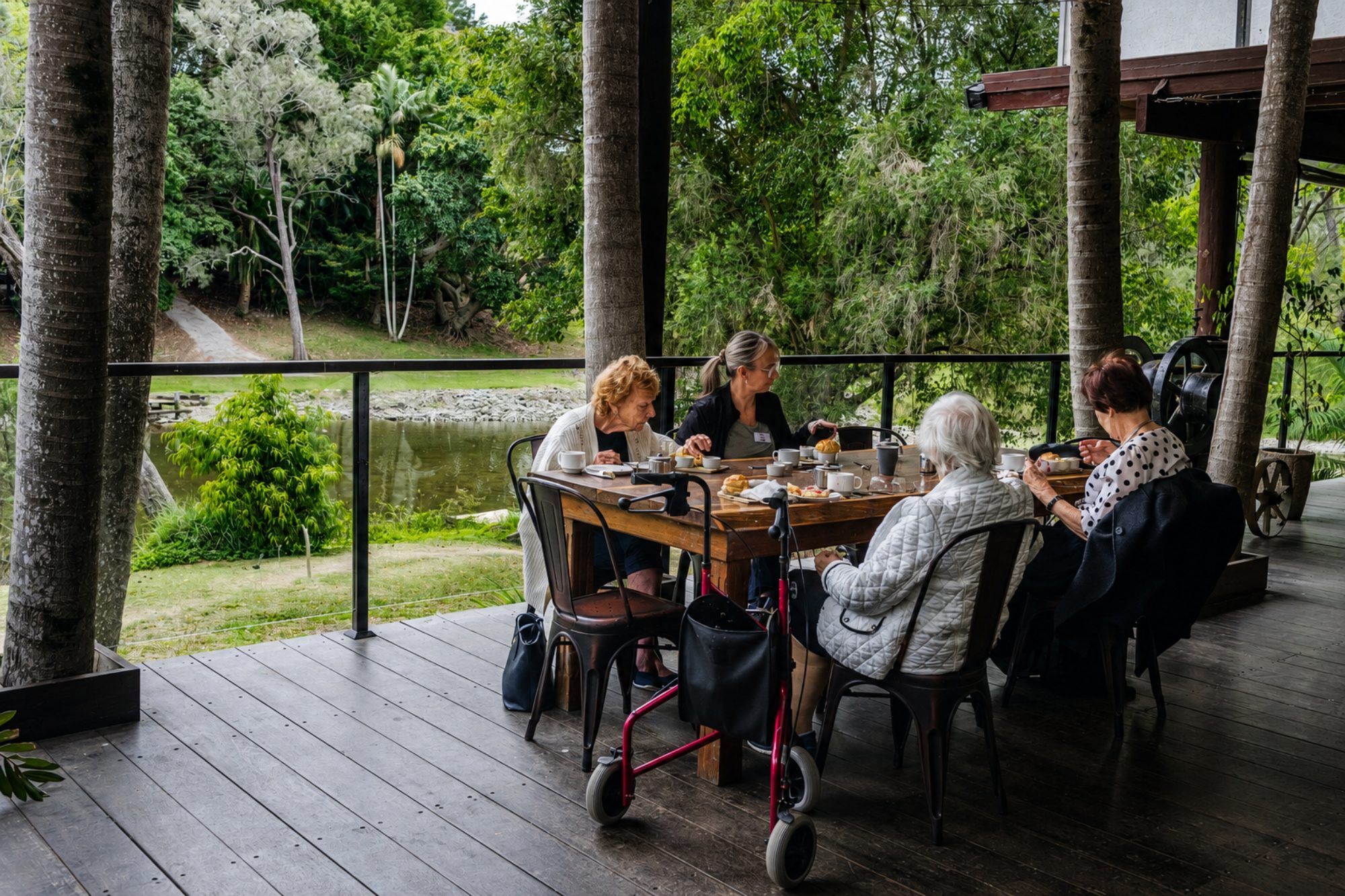 A seniors' group enjoying morning tea together on the dining deck overlooking the river at Historic Rivermill