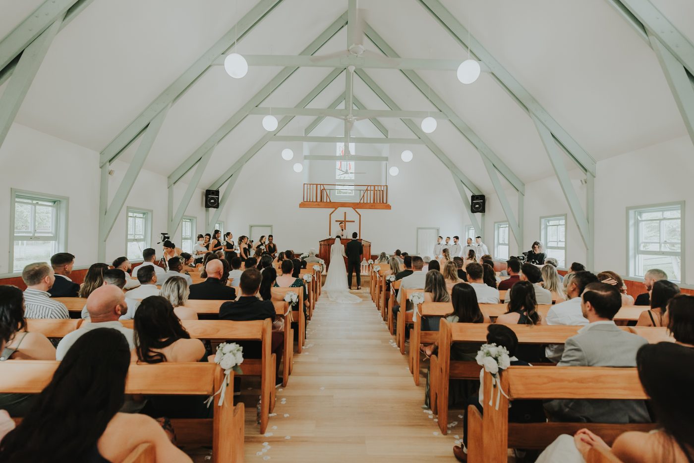 Inside the wedding chapel at Historic Rivermill, timber pews and sage-green trusses